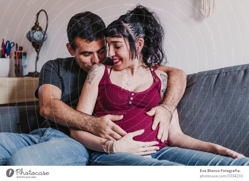 young couple at home hugging. Happy Pregnant woman smiling Couple Love Woman Parents expecting Home Sofa Embrace Kissing parenthood motherhood Husband Wife