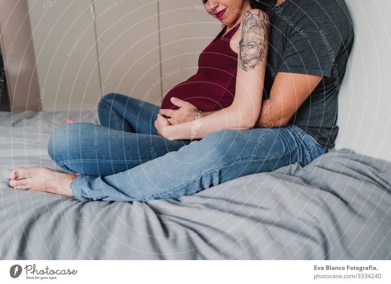 young couple at home hugging. Happy Pregnant woman smiling Couple Love Woman Parents expecting Home Sofa Embrace Kissing parenthood motherhood Husband Wife