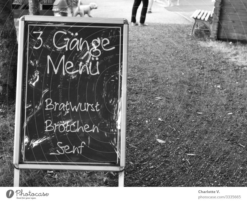 The display board of a snack bar promises a three-course menu consisting of bratwurst, bread rolls and mustard for purists. Culinary delights in black and white.