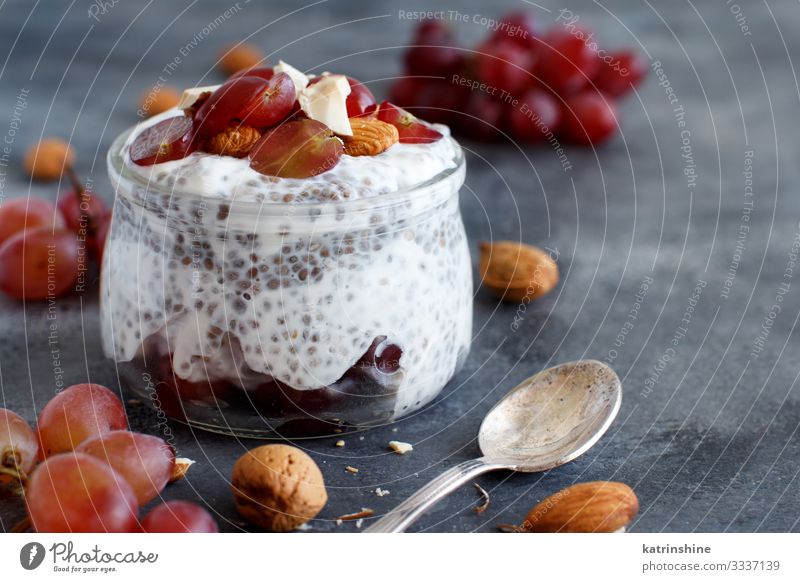 Chia pudding parfait with red grapes and almonds Yoghurt Fruit Dessert Eating Breakfast Diet Spoon Dark Gray White jar chia Bunch of grapes nuts Pudding seed