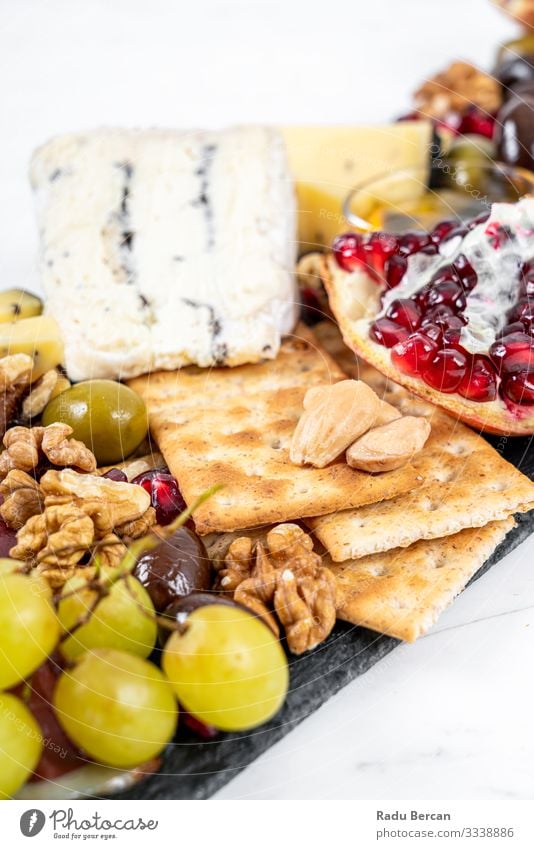 Food Platter With Truffle Cheese, Duck Breast, Brie Cheese, Pecan Nuts, Pomegranate Seeds, Grapes, Almonds, Honey, Olives and Crackers on White Marble Background