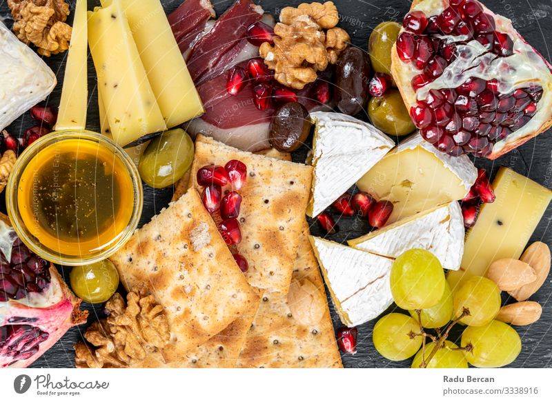 Food Platter With Truffle Cheese, Duck Breast, Brie Cheese, Pecan Nuts, Pomegranate Seeds, Grapes, Almonds, Honey, Olives and Crackers crackers almonds