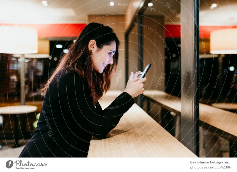 young woman using mobile phone in a cafe or restaurant indoors. Technology and lifestyle Woman Cellphone Interior shot Restaurant Café Window Businesswoman