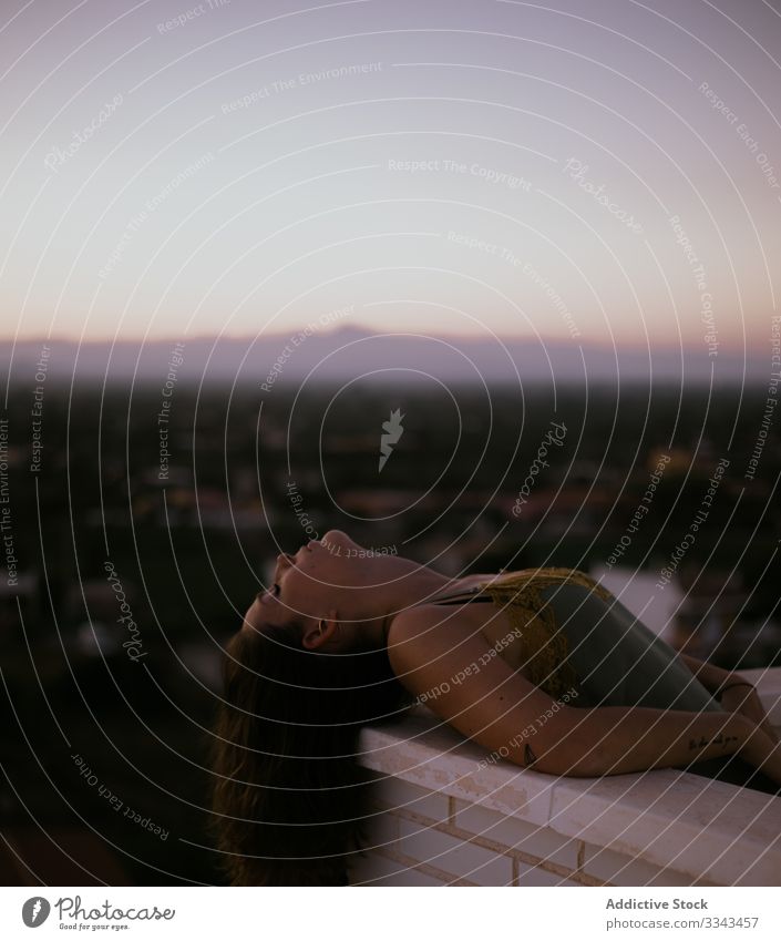 Serene woman leaning on balcony relax closed eyes lying resting fence terrace sunset evening nature sky heaven female lady lifestyle carefree peaceful serene