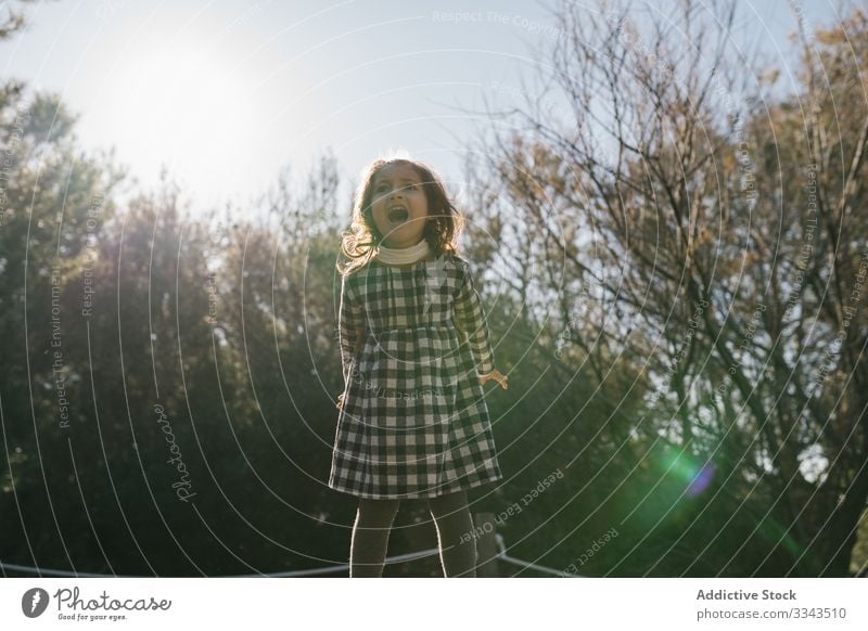 Playful girl jumping on ground child kid play weekend rest activity countryside trip ethnic day lovely vacation holiday inspiration childhood journey sky