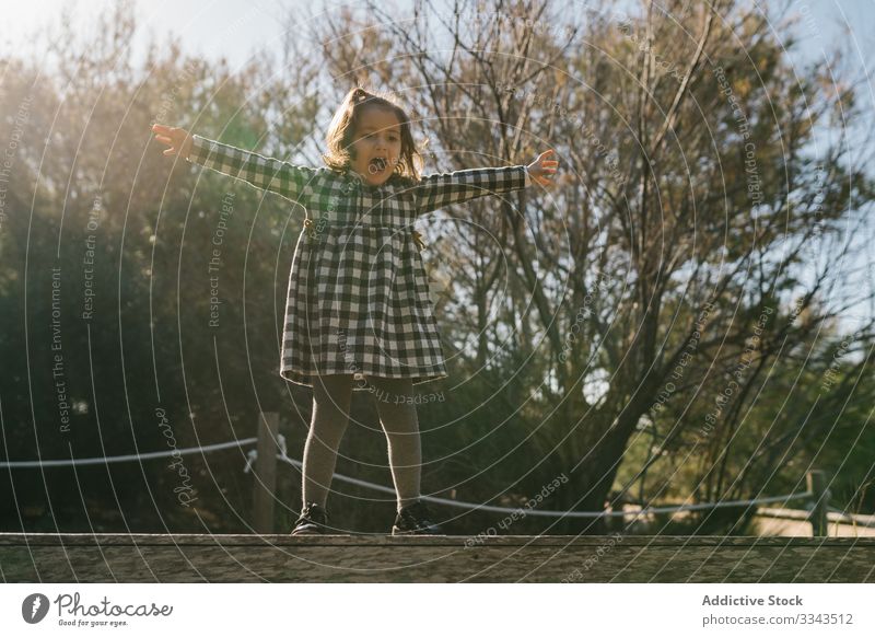 Playful girl jumping on ground child kid play weekend rest open arms activity countryside trip ethnic day lovely vacation holiday inspiration childhood journey