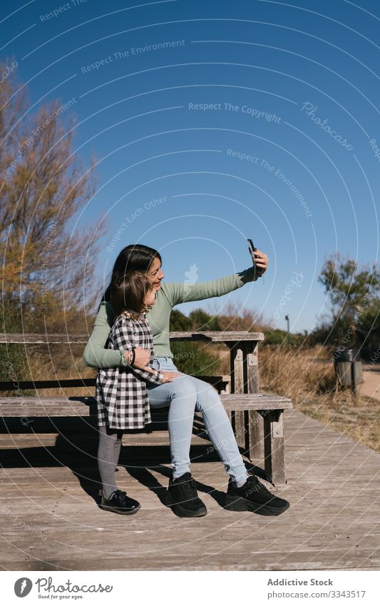 Happy ethnic mother taking selfie with kid child girl phone using photograph smile happy hug together relax nature cuddle smartphone childhood weekend affection