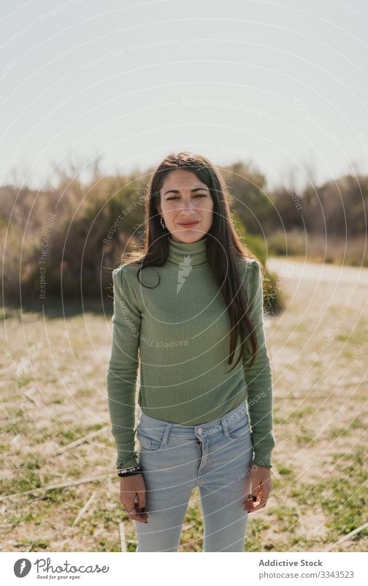 Pensive ethnic woman standing in countryside pensive thoughtful lifestyle think solution serious female casual imagination decision dilemma nature grass day