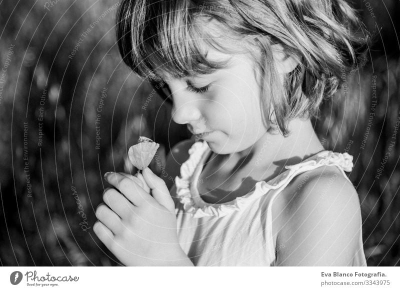 portrait outdoors at sunset of a beautiful kid girl among the flowers. Black and white photography. Innocence and children lifestyle. Summer Smiling heat wave