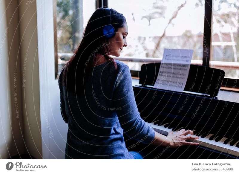 young woman holding playing piano by reading a music sheet. Music concept indoors. Back view Style Human being Key note Lessons Caucasian Press Chord Woman