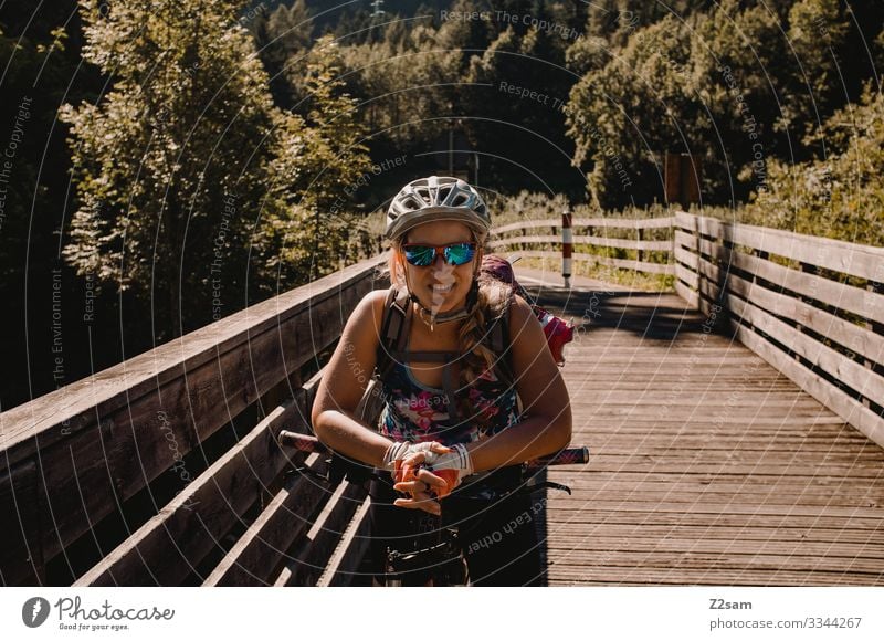 Young woman with the mountain bike in Italy alpine crossing Lake Garda Mountain bike mtb transalp Laughter Helmet Sunglasses Cycle path Summer Sports Nature