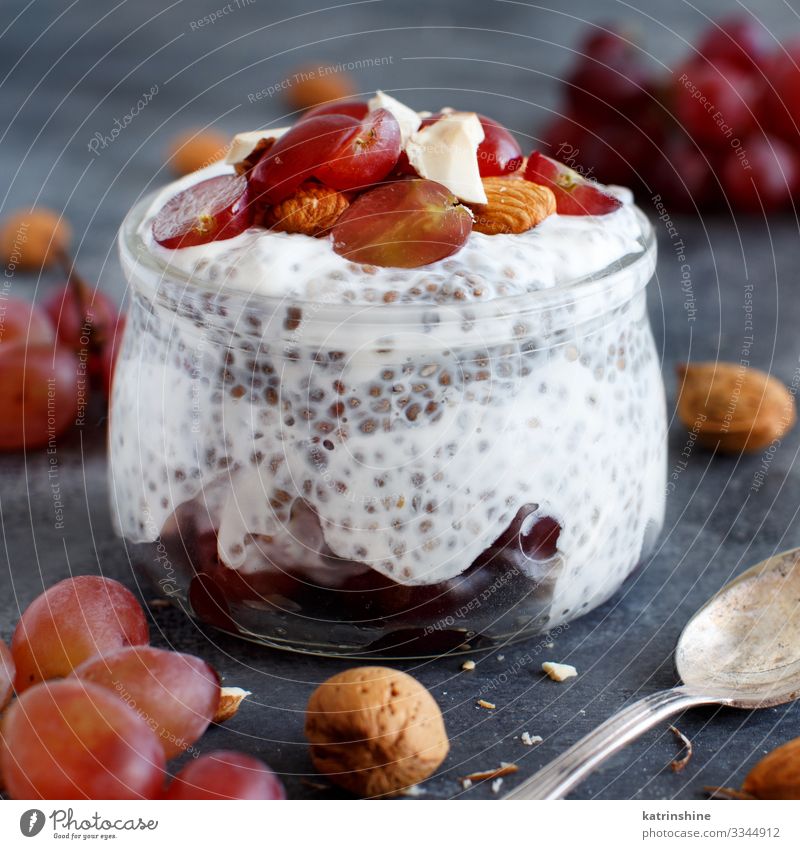 Chia pudding parfait with red grapes and almonds Yoghurt Fruit Dessert Eating Breakfast Diet Spoon Dark Gray White jar chia Bunch of grapes nuts Pudding seed