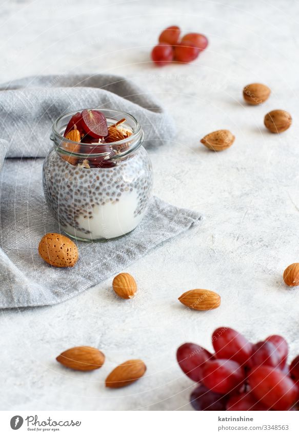 Chia pudding parfait with red grapes and almonds Yoghurt Fruit Dessert Eating Breakfast Diet Spoon White jar chia Bunch of grapes nuts Pudding seed chia seeds