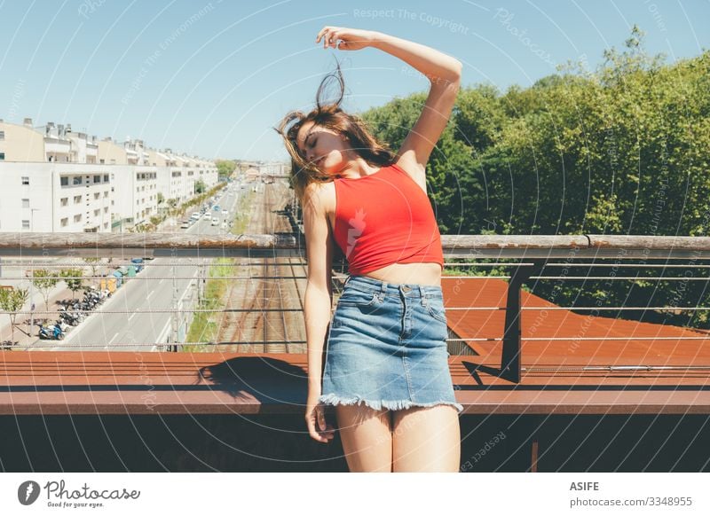 Young beautiful woman sunbathing on a bridge over the city Lifestyle Joy Happy Beautiful Relaxation Leisure and hobbies Summer Sun Woman Adults Arm Nature Wind