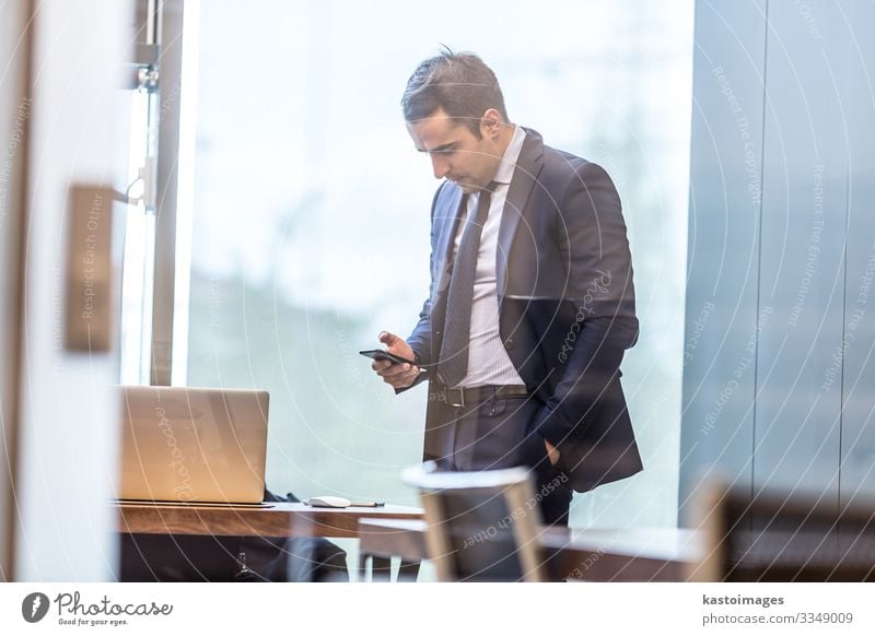 Businessman looking at smart phone in modern corporate office. Elegant Desk Work and employment Profession Workplace Office Company To talk Telephone Computer