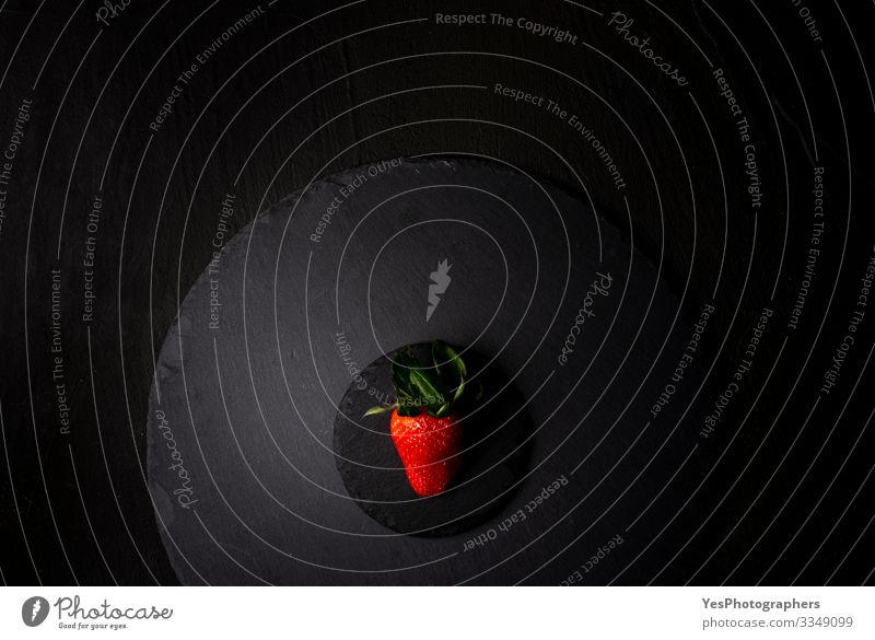 Single strawberry on a black granite plate. Above view Fruit Dessert Organic produce Diet Fresh Delicious Natural above view Berries black plate flat lay food