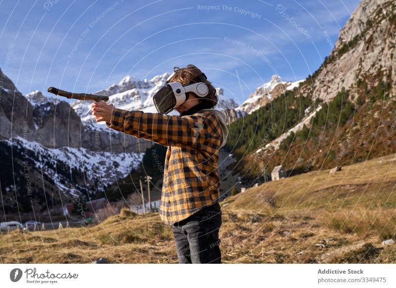 Boy standing on stone in VR glasses against mountain boy vr nature valley virtual stick reality headset modern device entertainment explore terrain technology