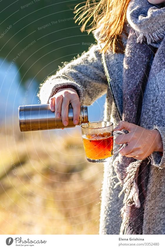 A young girl pours herbal tea into a glass mug. Tea Lifestyle Joy Wellness Relaxation Leisure and hobbies Sun Woman Adults Hand Autumn Wind Warmth Leaf Park