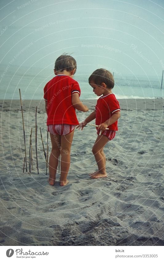 Two little girls in partner look, playing on the beach, building a fence with sticks and listening to the sea. Parenting Child Freedom Playing luck Nature