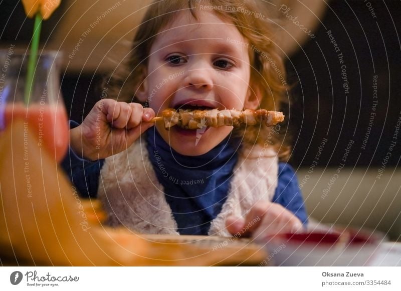 Little blonde girl eats kebab with pleasure. Dinner time. Looking into the camera Interior shot Dish meal time enjoyment Tasty Meal food little girl kid