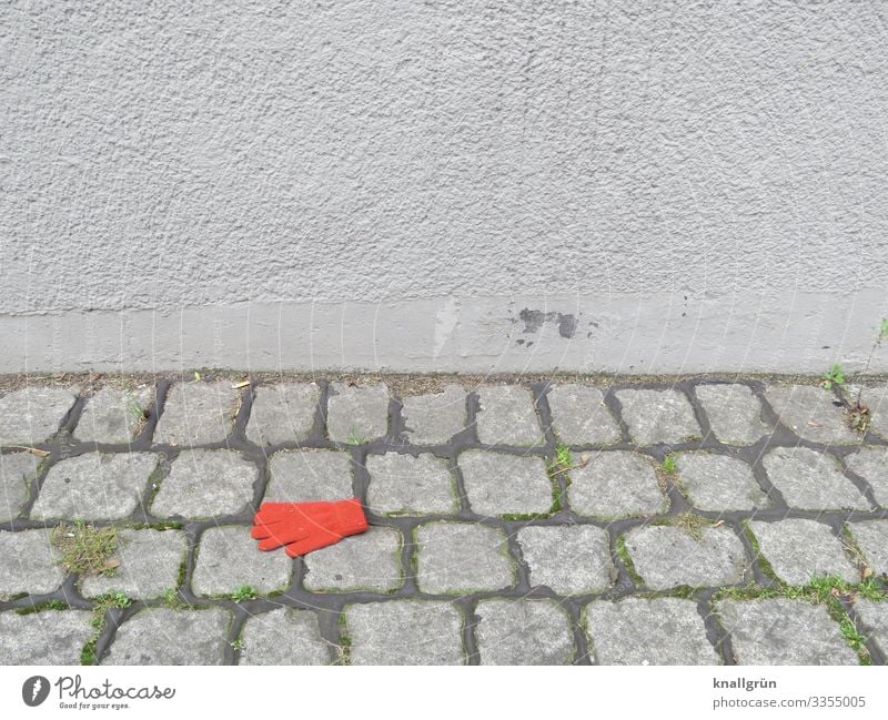 on one's own Town Wall (barrier) Wall (building) Fashion Clothing Accessory Gloves Cobblestones Lie Gray Red Emotions Sadness Loneliness Colour Divide Lose