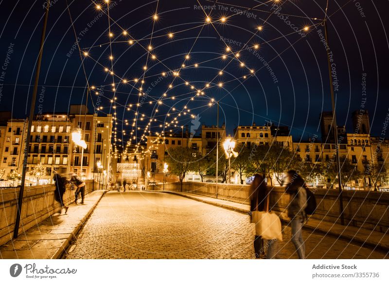 People walking on illuminated bridge in city in evening people illumination leaning urban architecture building night twilight landmark dusk girona spain