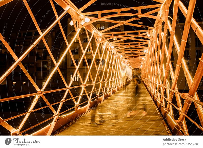 People walking on illuminated bridge construction in evening people illumination city leaning urban architecture building night twilight landmark dusk girona