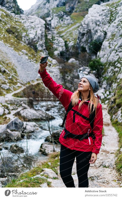 Woman with backpack taking selfie on smartphone on background of mountains woman tourist using travel nature device gadget dry peak photographing trekking