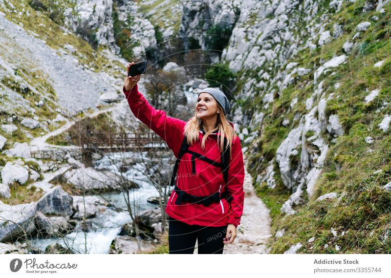 Woman with backpack taking selfie on smartphone on background of mountains woman tourist using travel nature device gadget dry peak photographing trekking