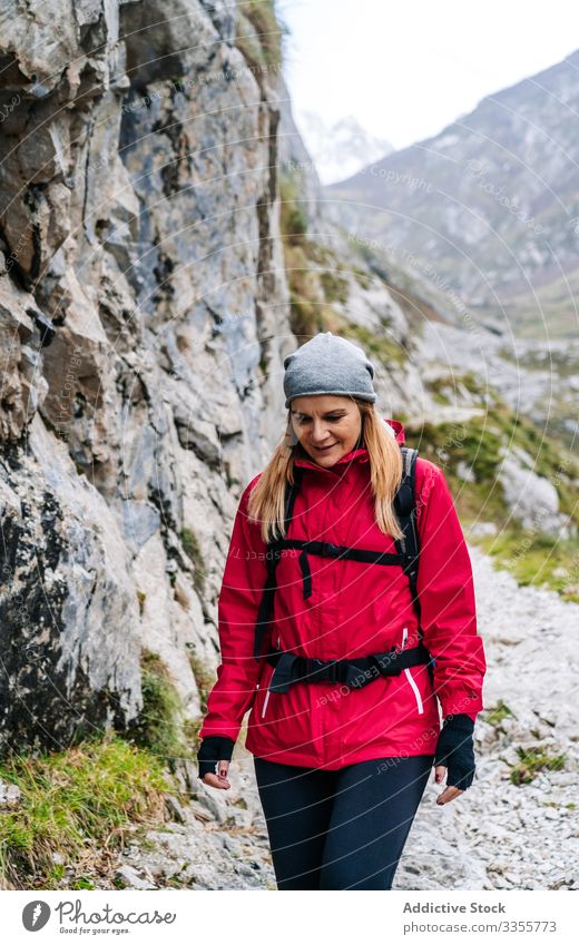 Tourist with backpack walking among high rocks woman tourist peak female mountain hill travel nature trekking landscape sky tourism adventure dangerous extreme