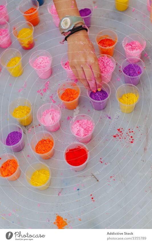 Crop woman taking paint from table festival celebration cup dry colorful set park event pigment dye multicolored bright vivid vibrant holiday traditional many