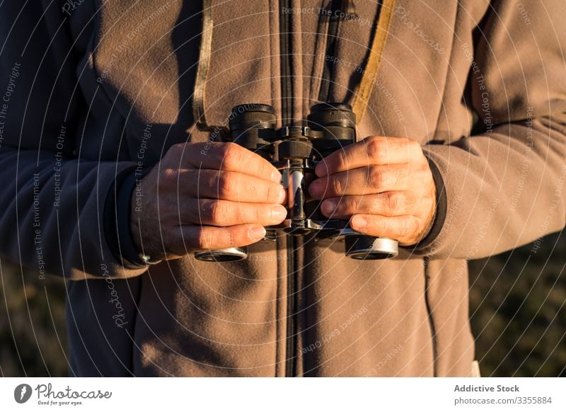 Anonymous man holding old binoculars in a lagoon water landscape forest lake wetland adventure wild fauna blue sky sunny scenic copy space nature natural