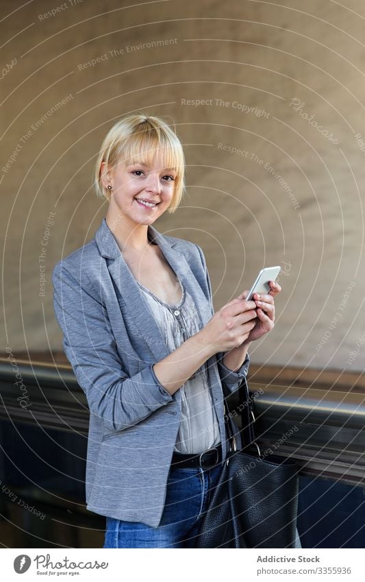 Smiling businesswoman with smartphone stylish young cheerful handrail female professional person beautiful smiling using browsing looking at camera attractive