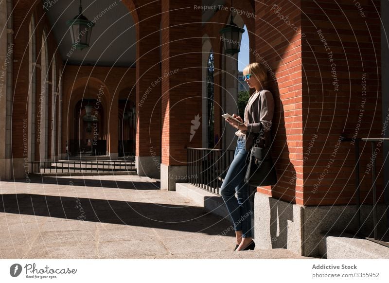 Businesswoman with tablet at wall businesswoman stylish young browsing watching leaning brick wall female professional person beautiful attractive sunglasses