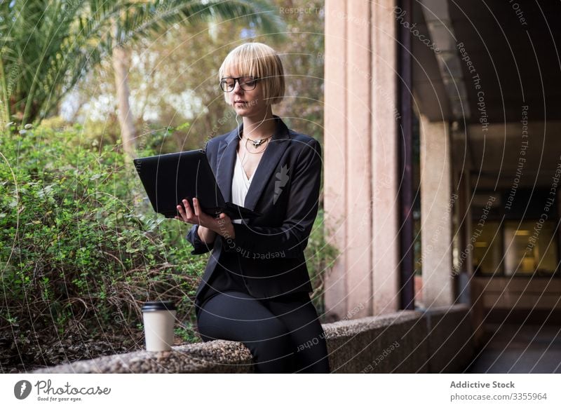 Young businesswoman sitting and using tablet stylish young browsing watching park fence female professional person beautiful attractive entrepreneur garden