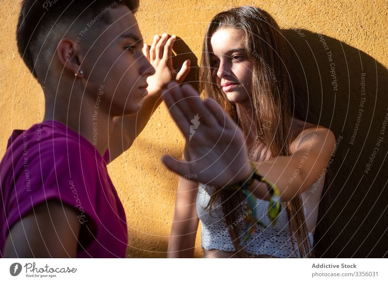 Serious female leaning on wall standing near ethnic guy showing stop sign friend argue conflict quarrel serious reject problem signal decision relationship