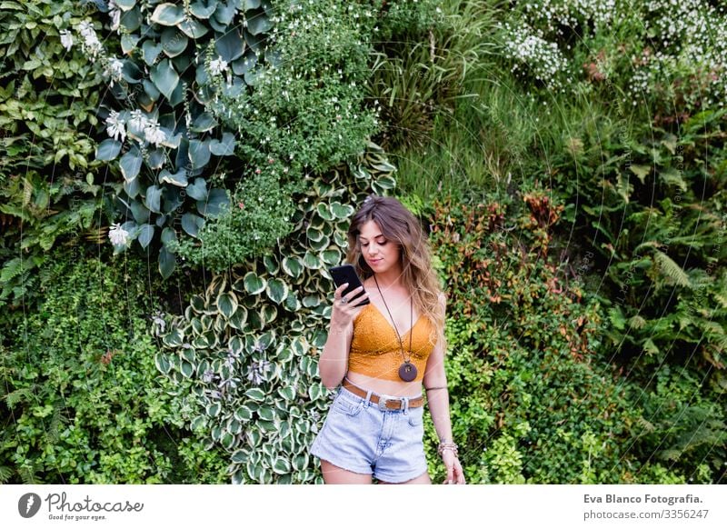 young blonde beautiful woman at the street using mobile phone and smiling. Lifestyle outdoors. Summertime, Green background Smart Town Happy Human being Smiling