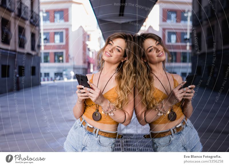 young blonde beautiful woman at the street using mobile phone. Glass reflection. Lifestyle outdoors. Summertime. Smart To call someone (telephone) Town Happy