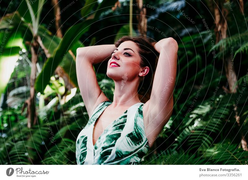 portrait of beautiful blonde young woman smiling at sunset in a green house surrounded by tropical plants. Happiness and lifestyle concept Caucasian toothy Cute