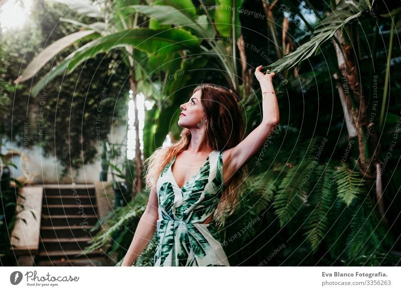 portrait of beautiful blonde young woman smiling at sunset in a green house surrounded by tropical plants. Happiness and lifestyle concept Caucasian toothy Cute