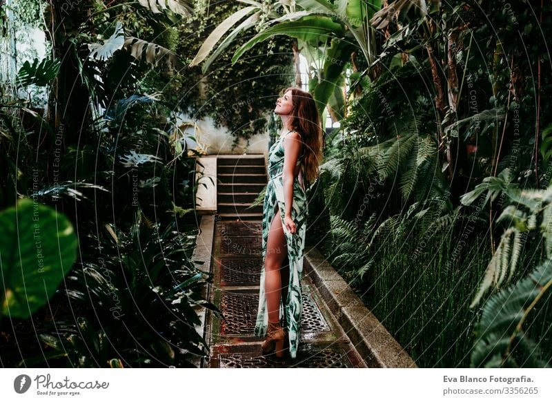 portrait of beautiful blonde young woman smiling at sunset in a green house surrounded by tropical plants. Happiness and lifestyle concept Caucasian toothy Cute