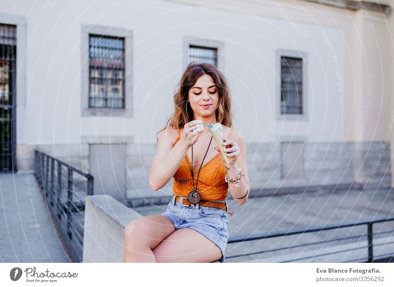 Beautiful young caucasian woman eating mint ice cream at the city street on a sunny day. Happy face smiling. Urban and summer lifestyle Day Street Woman Sunbeam