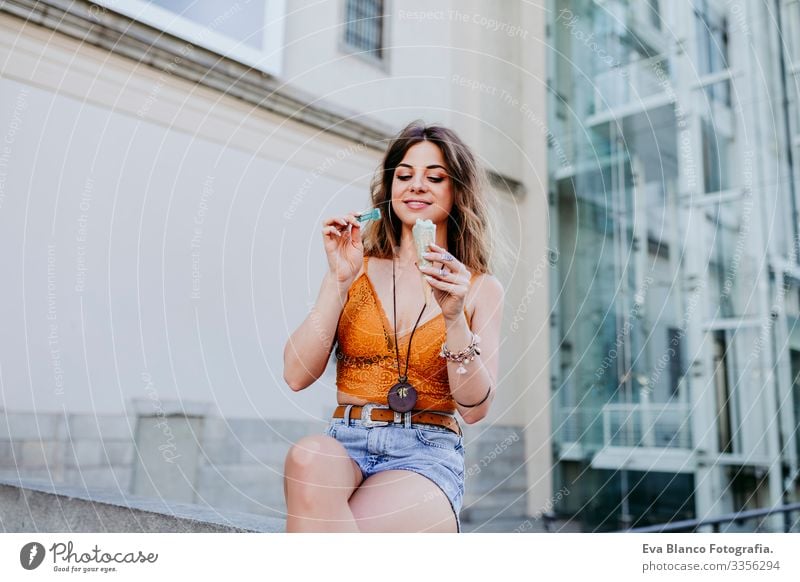 Beautiful young caucasian woman eating mint ice cream at the city street on a sunny day. Happy face smiling. Urban and summer lifestyle Day Street Woman Sunbeam