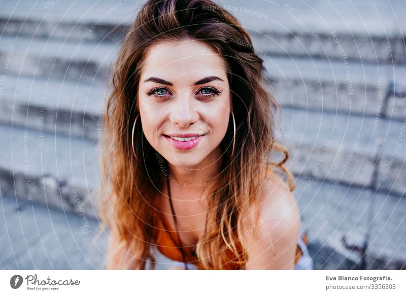 Beautiful young caucasian woman sitting on stairs at the city street on a sunny day. Happy face smiling looking at the camera. Urban lifestyle Day Street Woman