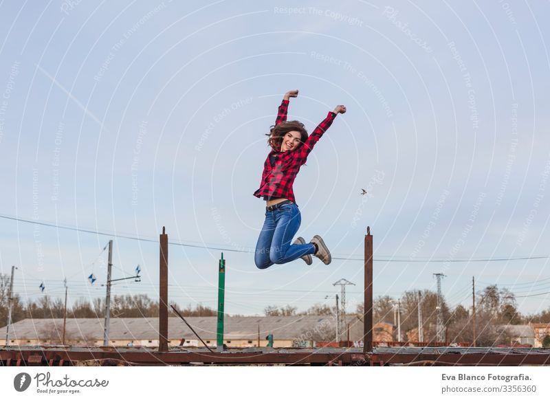 young beautiful woman jumping and feeling happy. She is wearing casual clothes. Outdoors city background. Lifestyle Town Hat Beautiful Stand Attractive Mobile