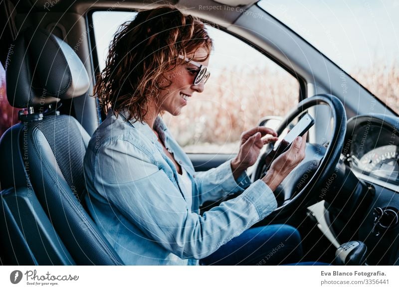 young beautiful woman using mobile phone in a car. travel concept Cellphone Technology Woman Youth (Young adults) Driving Car Sunbeam Sunglasses