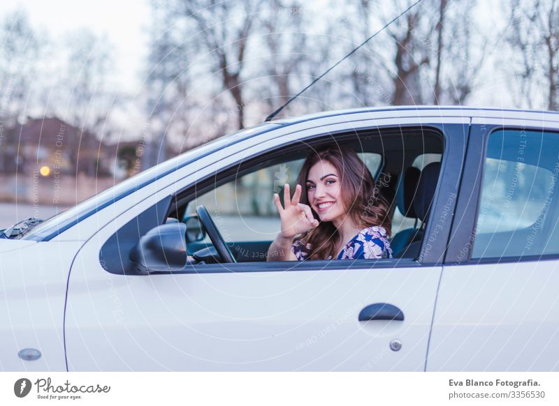 Young woman driving a car in the city. Portrait of a beautiful woman in a car, looking out of the window and smiling. Travel and vacations concepts