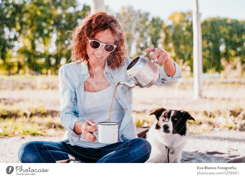 young woman pouring tea with pot outdoors. Using stove. camping concept Youth (Young adults) Woman Camping Pot Stove & Oven Sunset preparing Hot Tea Teapot