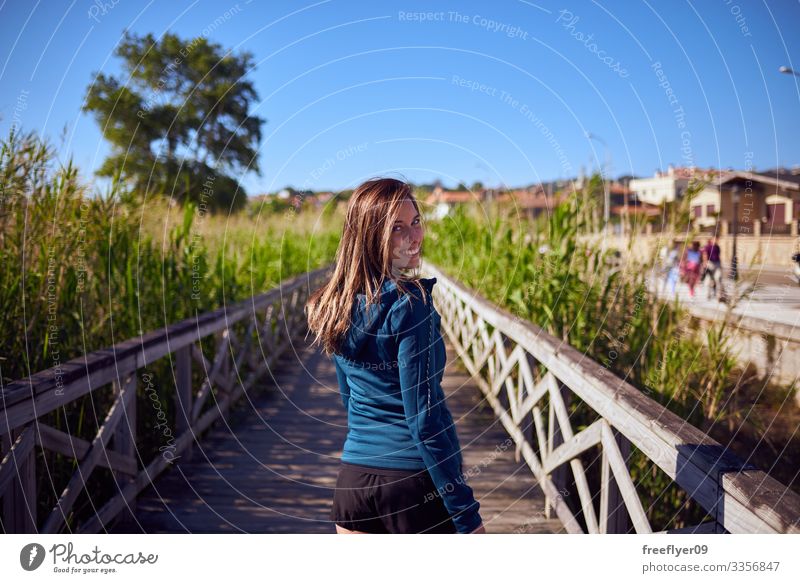 Young woman in sports clothes walking by a wooden walkway in Playa America, Vigo activity rail vigo blue 1 young tour tourism nature boardwalk galicia heaven