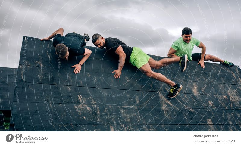 Participants in obstacle course climbing inverted wall Lifestyle Sports Climbing Mountaineering Human being Man Adults Group Authentic Strong Black Effort